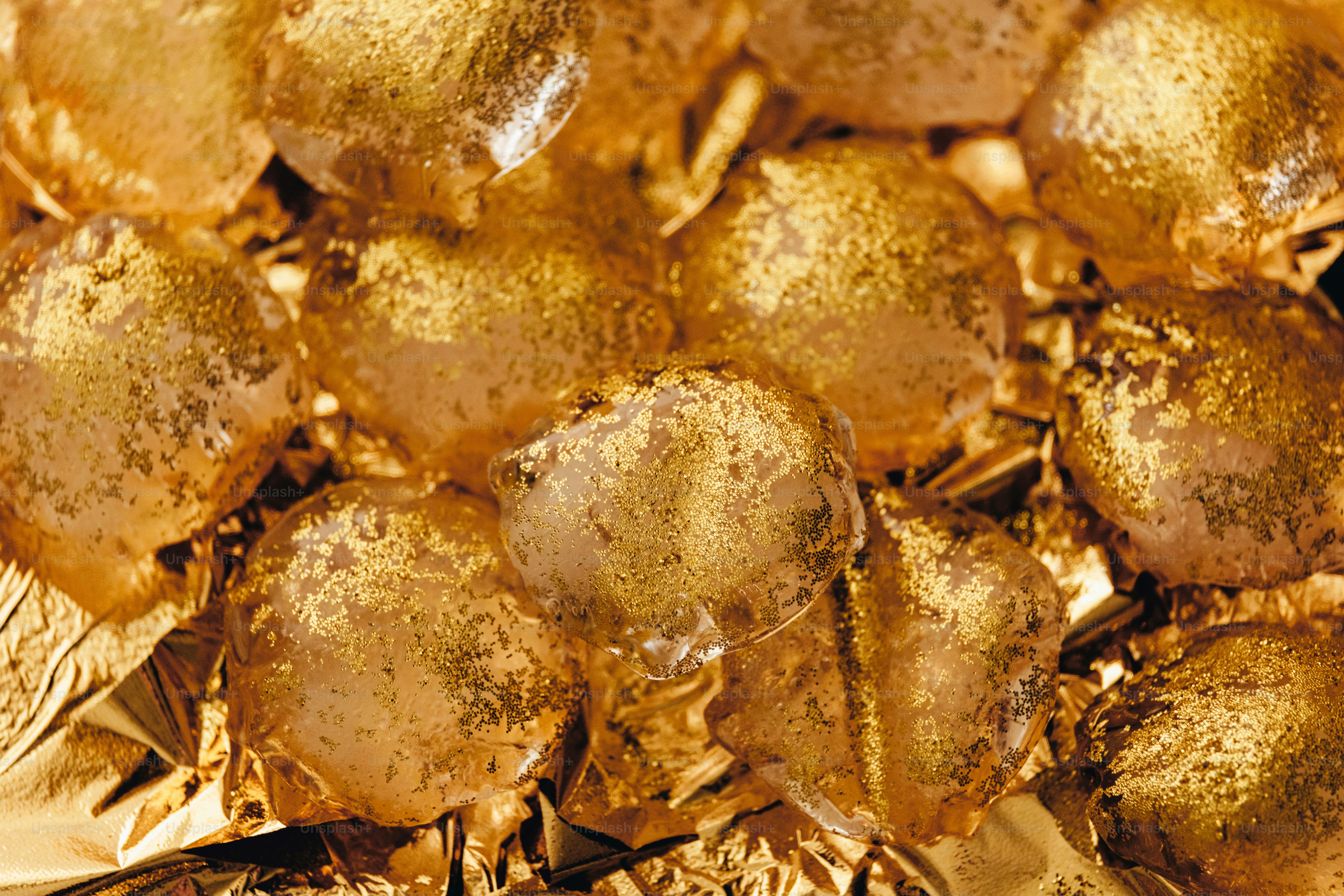 Golden ice cubes scattered on crinkled gold foil